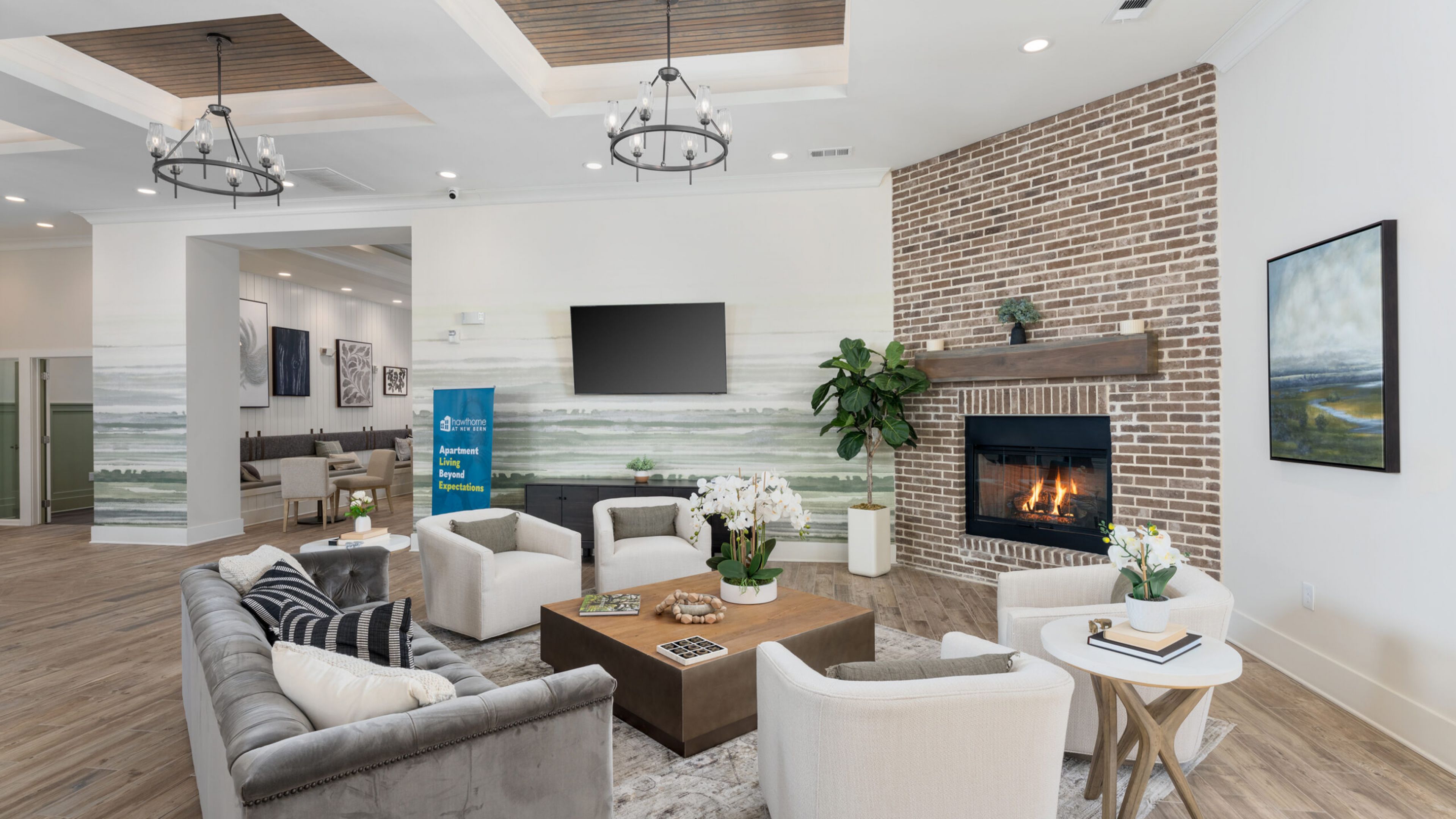 Hawthorne at New Bern modern living room with a gray sofa, armchair, coffee tables, wall art, and bar cart by a mirror.