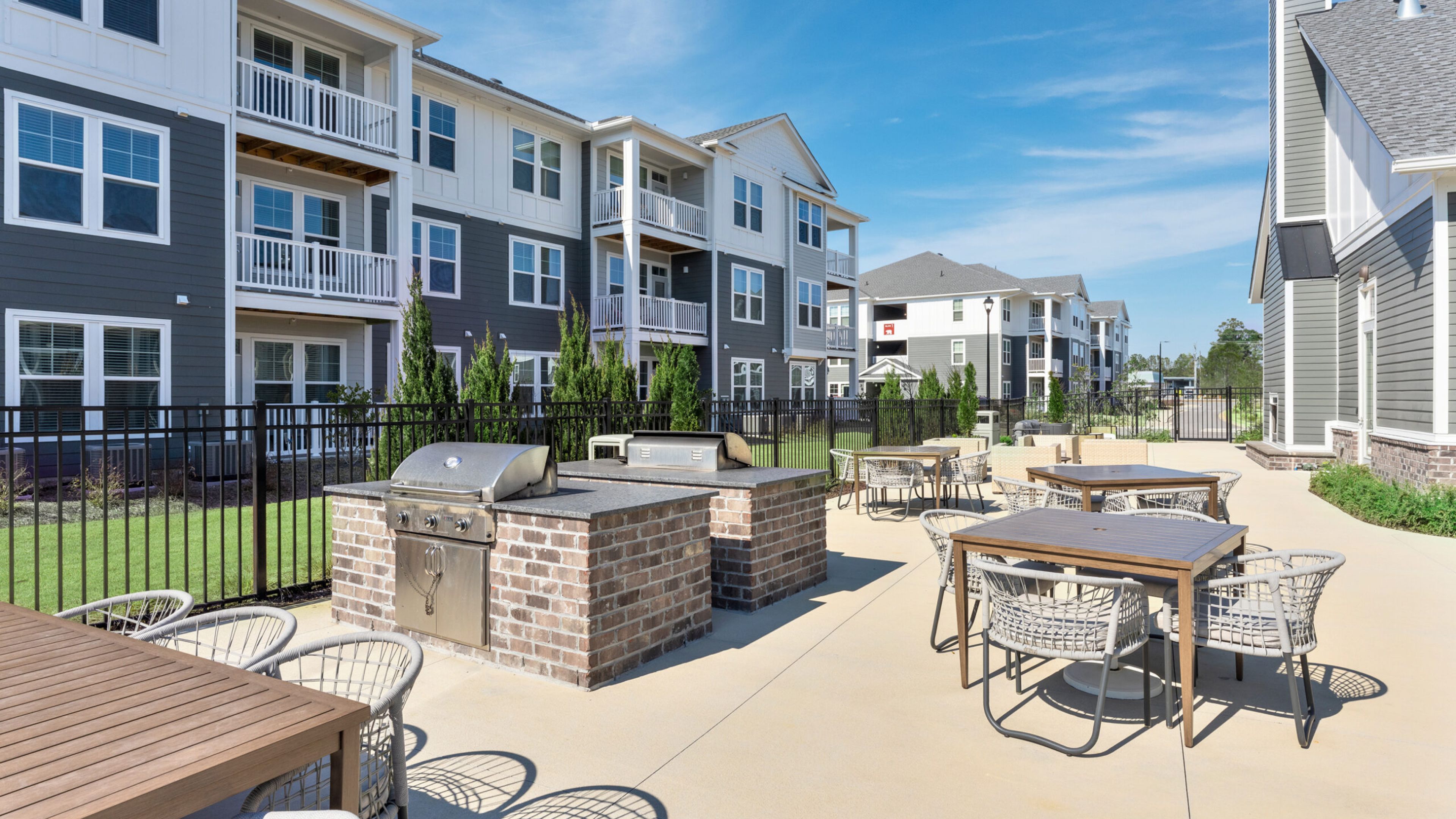 Hawthorne at New Bern outdoor swimming pool with lounge chairs next to a modern apartment complex on a sunny day.